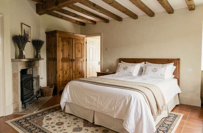 Chambre d'hôtes chaleureuse avec poutres apparentes et literie en lin blanc dans un manoir normand